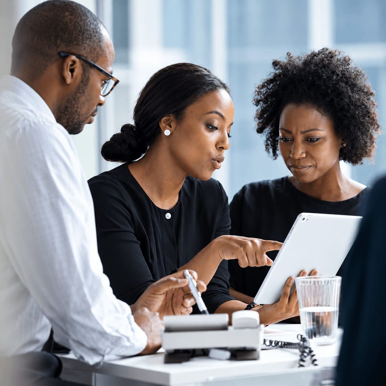 Three people working through a venture review on a tablet